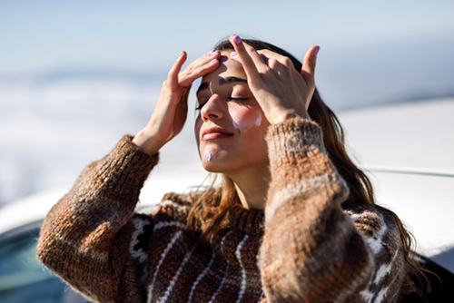 Woman applying sunscreen in the Winter to help prevent skin cancer